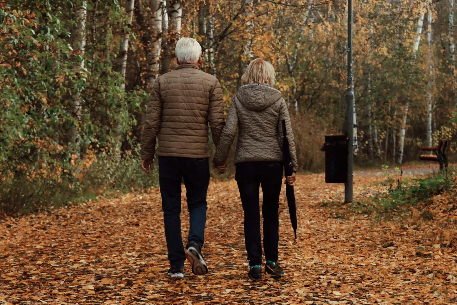 Older couple enjoying a peaceful walk through an autumn park