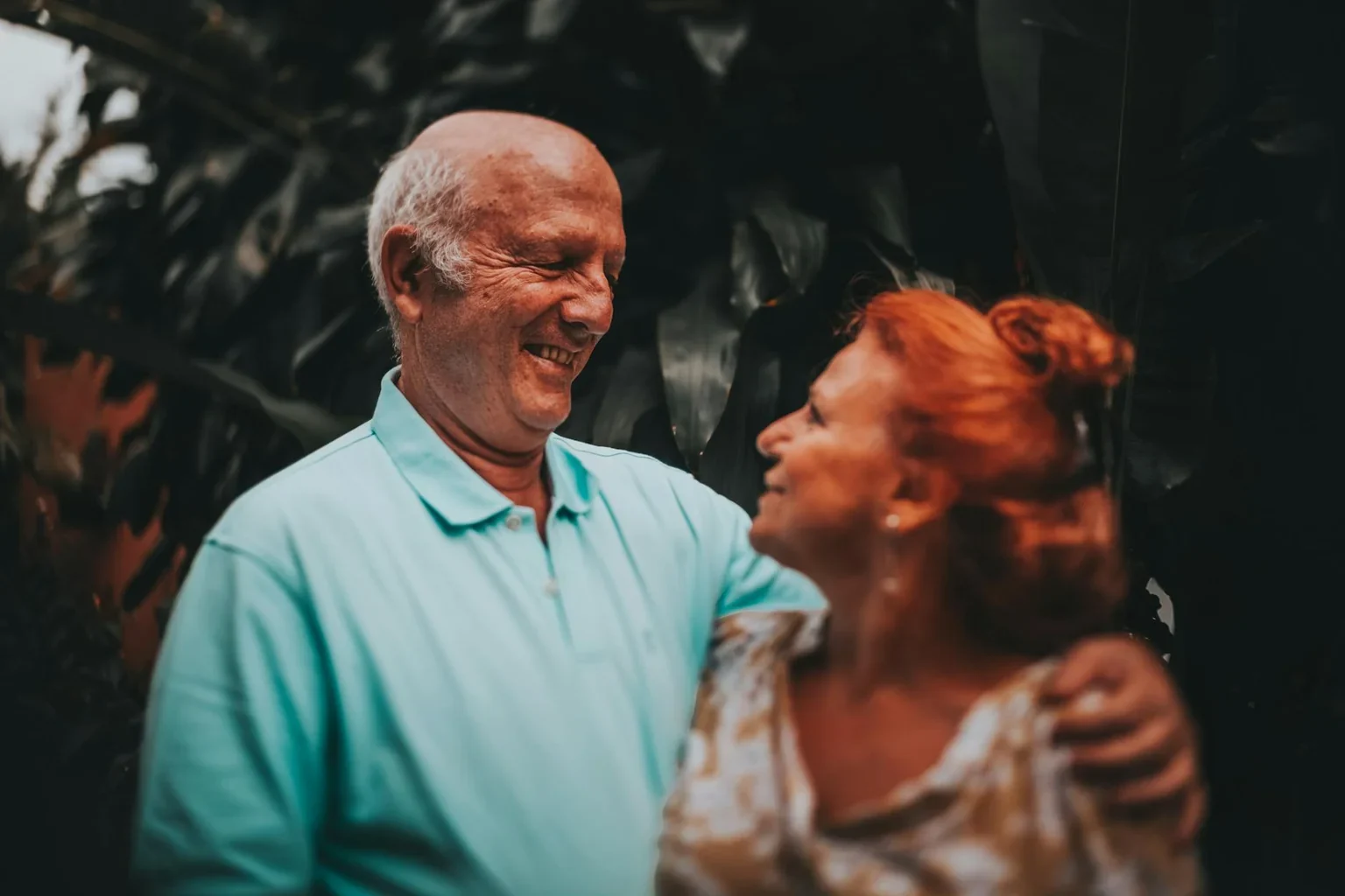 Smiling elderly couple embracing outdoors after recovering knee mobility