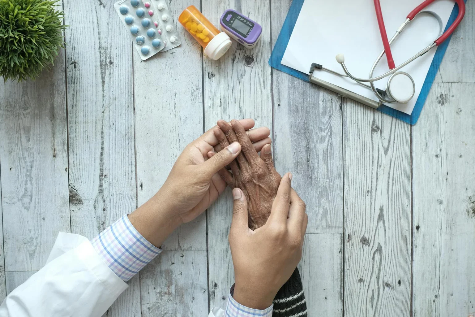 Doctor holding the hand of an elderly patient during follow-up consultation
